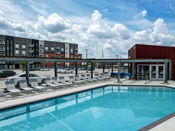 A large swimming pool with lounge chairs and a building in the background.